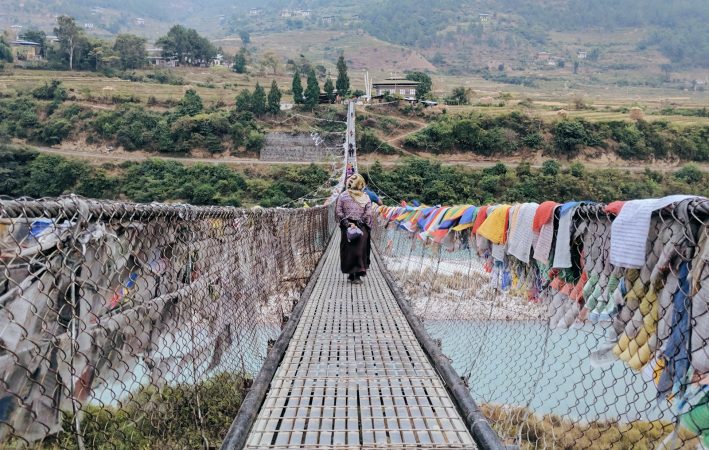 person walking on bridge with clothes hanging